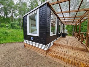 eine schwarz-weiße Hütte mit einer Holzterrasse in der Unterkunft Mansikkaharju Holiday Camp in Leppävirta