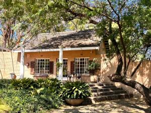una pequeña casa de ladrillo con porche y escaleras en Farm stay at Saffron Cottage on Haldon Estate, en Bloemfontein