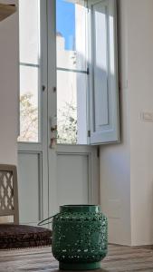 un vase vert assis sur le sol devant une porte dans l'établissement La Cour des jasmins charm & relax à 15 mn de la mer, à Matino