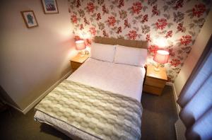 a bedroom with a bed with two lamps on two tables at Fladda Chuain Holiday Home in Kilmuir