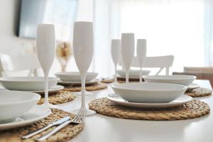 une table recouverte de plaques et bols blancs et d'argenterie dans l'établissement Apartment Boho, à Torre de la Horadada