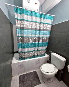a bathroom with a toilet and a shower curtain at "Sun" Bayview apartment in Lixouri