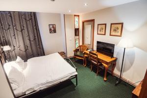 a hotel room with a bed and a desk and a computer at Šumava Inn in Kvilda