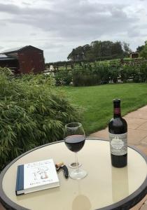 a bottle of wine and a glass on a table at Primrose Holiday Cottage, Dog Friendly, Hot Tub, Winestead, East Yorkshire Coast in Hull