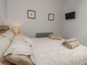 una camera da letto con un grande letto bianco con asciugamani di Primrose Holiday Cottage, Dog Friendly, Hot Tub, Winestead, East Yorkshire Coast a Hull