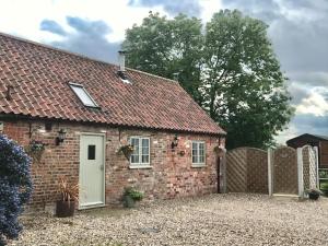 a brick house with a white door and a fence at Primrose Holiday Cottage, Dog Friendly, Hot Tub, Winestead, East Yorkshire Coast in Hull