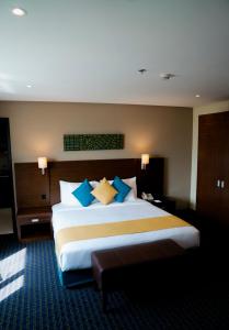 een slaapkamer met een groot bed met blauwe en gele kussens bij Best Western Premier Muscat in Muscat