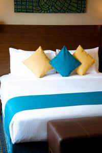 Una cama con almohadas azules y amarillas. en Best Western Premier Muscat en Mascate