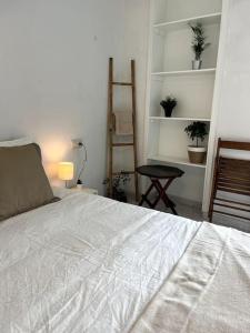 a bedroom with a white bed and a chair and shelves at El apartamento de Ordes in Órdenes