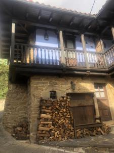 a building with a balcony and a pile of wood at La Forna in Caso