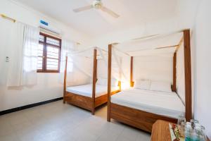 a bedroom with two beds and a window at Savi House Nungwi in Nungwi