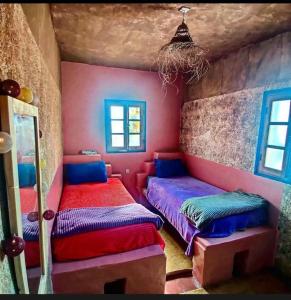 two beds in a room with colorful walls and windows at Hippie Chic House in Sidi Kaouki
