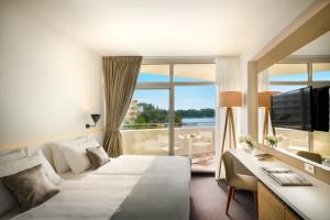a hotel room with a bed and a desk and a television at Remisens Hotel Albatros-All inclusive in Cavtat