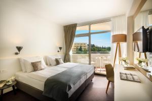 a hotel room with a bed and a large window at Remisens Hotel Albatros-All inclusive in Cavtat