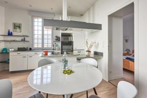 een witte keuken met een witte tafel en stoelen bij Château de Chimay - Appt en front de mer in Barneville-Carteret