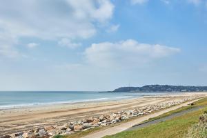 a beach with a bunch of rocks and the ocean at Château de Chimay - Appt en front de mer in Barneville-Carteret +5 photos