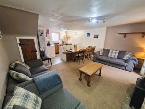 uma sala de estar com um sofá, uma mesa e uma cozinha em Ash Cottage em Hope