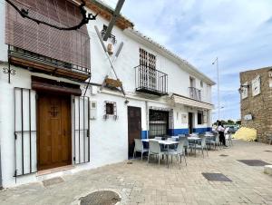 un bâtiment blanc avec des tables et des chaises devant lui dans l'établissement Casa en el Puerto de Denia, à Dénia