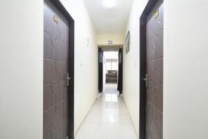 a hallway with two brown doors and a white tile floor at FabExpress Golden Villa in Indore