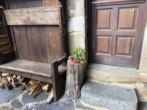 a wooden bench next to a door with a potted plant at La Forna in Caso