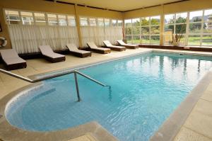 a large swimming pool with lounge chairs in a building at Marcin Hotel in Carilo