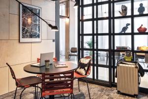 a room with a table with a laptop and chairs at Moxy Katowice Airport in Pyrzowice