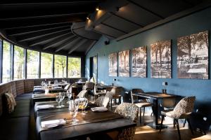 een restaurant met houten tafels, stoelen en ramen bij Hotel Restaurant De Roosterhoeve in Roosteren