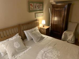 ein Schlafzimmer mit einem Bett mit weißen Kissen und einem Stuhl in der Unterkunft Baita Le Pozze in Abetone