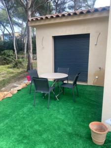 um pátio com uma mesa e cadeiras sobre relva verde em Appartement T2 Sanary sur mer em Sanary-sur-Mer