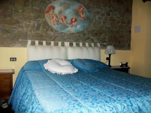 ein Schlafzimmer mit einem blauen Bett und einer Steinmauer in der Unterkunft Country Farm in Vernio