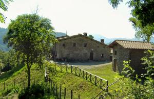 uma velha casa de pedra numa colina com uma cerca em Country Farm em Vernio