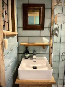 a bathroom with a white sink and a mirror at The Walnut Wagon in the heart of Mells. in Frome