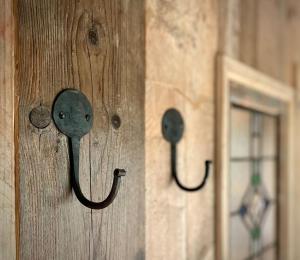 a wooden door with two hooks on a wall at The Walnut Wagon in the heart of Mells. in Frome