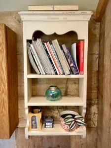 a book shelf with books and a vase on it at The Walnut Wagon in the heart of Mells. in Frome