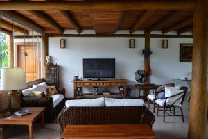 a living room with a couch and a tv at Gidu Ilhabela in Ilhabela