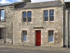 a brick building with a red door on a street at Victorias Haven in Kirkcaldy