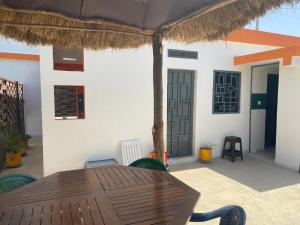 eine Terrasse mit einem Holztisch und einem Strohschirm in der Unterkunft Studio neuf independant dans villa in Ouoran