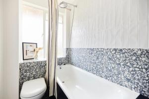 ein Badezimmer mit einer Badewanne, einem WC und einem Waschbecken in der Unterkunft The London Escape - Modish 1BDR Flat in London