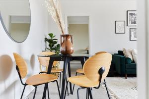 a dining room with a vase on a table and chairs at The London Escape - Modish 1BDR Flat in London