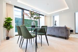 a dining room with a glass table and green chairs at Haverstock Hill Serviced Apartments by Concept Apartments in London