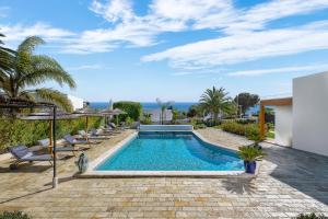 una piscina en un patio con sillas y el océano en Romantik Villa, en Salema