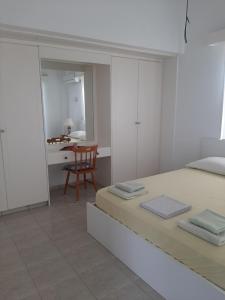 a white bedroom with a bed and a table at Pangeras Apartments in Pissouri