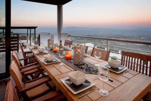una mesa de madera con platos y vasos en el balcón en Villa Arcadia, Kallepia, en Pafos