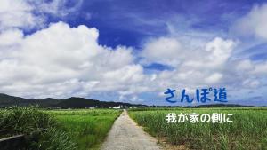 eine unbefestigte Straße in einem Feld unter einem wolkigen Himmel in der Unterkunft 民泊まったりん人 in Janadō