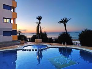 a swimming pool in front of a building and the ocean at ShoreHouse Apartamento Primera linea Playa Honda in Playa Honda