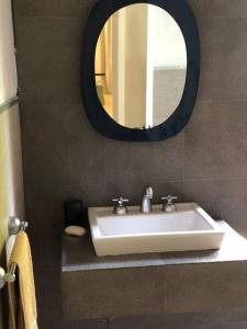 een badkamer met een witte wastafel en een spiegel bij Casa en callejón privado en Chacras de Coria con bicicleta in Ciudad Lujan de Cuyo