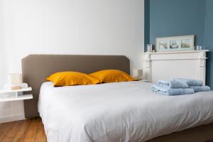 um quarto com uma cama com almofadas amarelas e paredes azuis em Appartement spacieux em Quimper