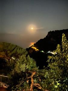Une pleine lune s'élevant au-dessus d'une montagne avec des arbres dans l'établissement B&B Casanova, à Agerola