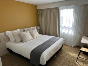 1 dormitorio con 1 cama grande con almohadas y ventana en Hôtel Akena Chauray-Niort, en Chauray