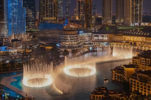 a group of water fountains in a city at night at Elite Royal Apartment - Full Burj Khalifa & Fountain View - Deluxe in Dubai